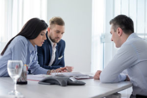 man and couple looking over and discussing information in a binder