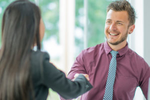 woman and smiling man client shake hands 