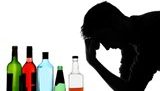 man holding his head in front of alcohol bottles